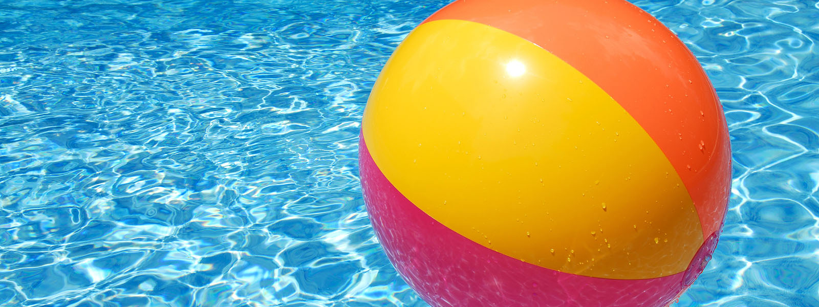 A colorful beach ball floating on the swimming pool.