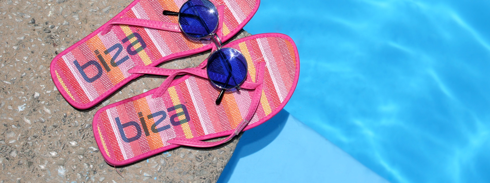 Sandals with the Biza logo on them next to a pool.